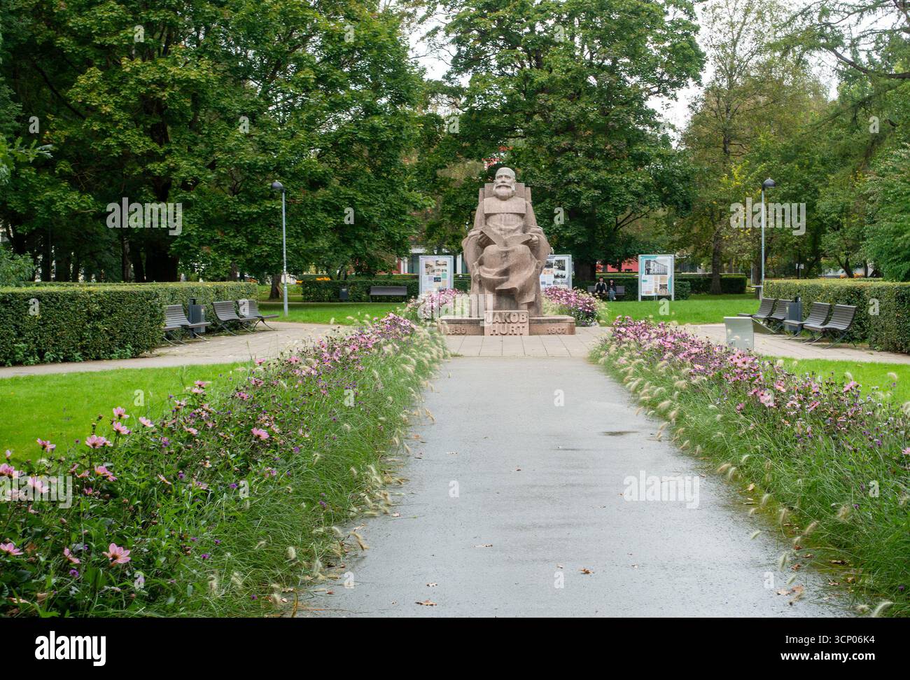 Monumento a Jakob Hurt a Tartu, Estonia, in onore del folclorista e della figura pubblica, circondato da un parco paesaggistico con fiori e panchine. Foto Stock