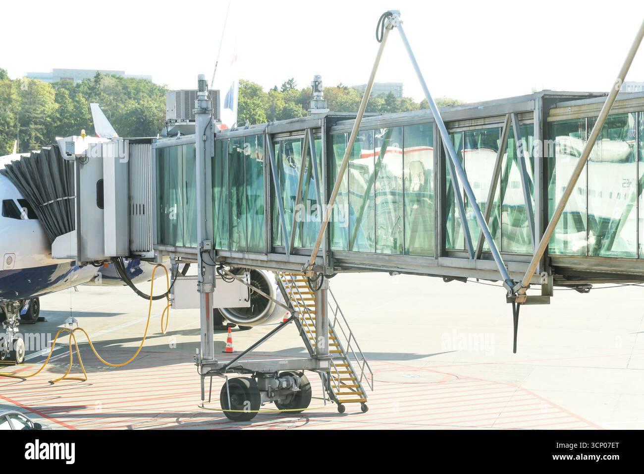 Ponte di imbarco passeggeri all'aeroporto. Jet in vetro collegato all'aereo. Moderna architettura dei trasporti. Viaggi e esperienze di volo. Terminale dell'aria. Foto Stock