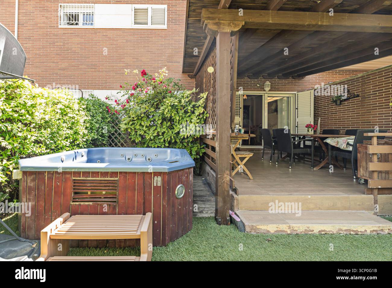 Giardino con terrazza con prato inglese, aiuole perenni e panche in legno integrate nel design paesaggistico Foto Stock