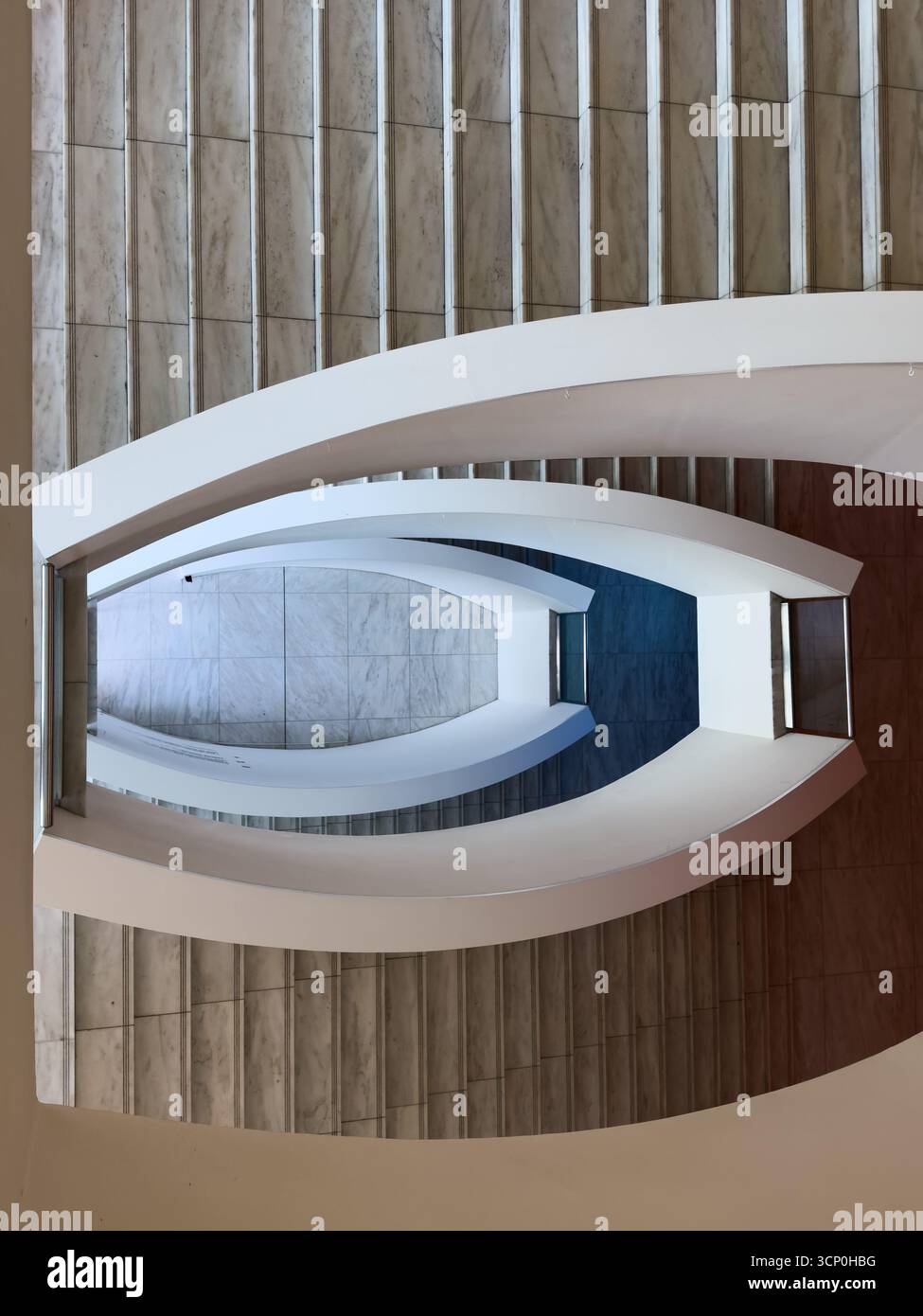 Vista aerea scale bianche curve circondate da pareti in marmo in interni architettonici contemporanei che formano simmetria e profondità a spirale Foto Stock