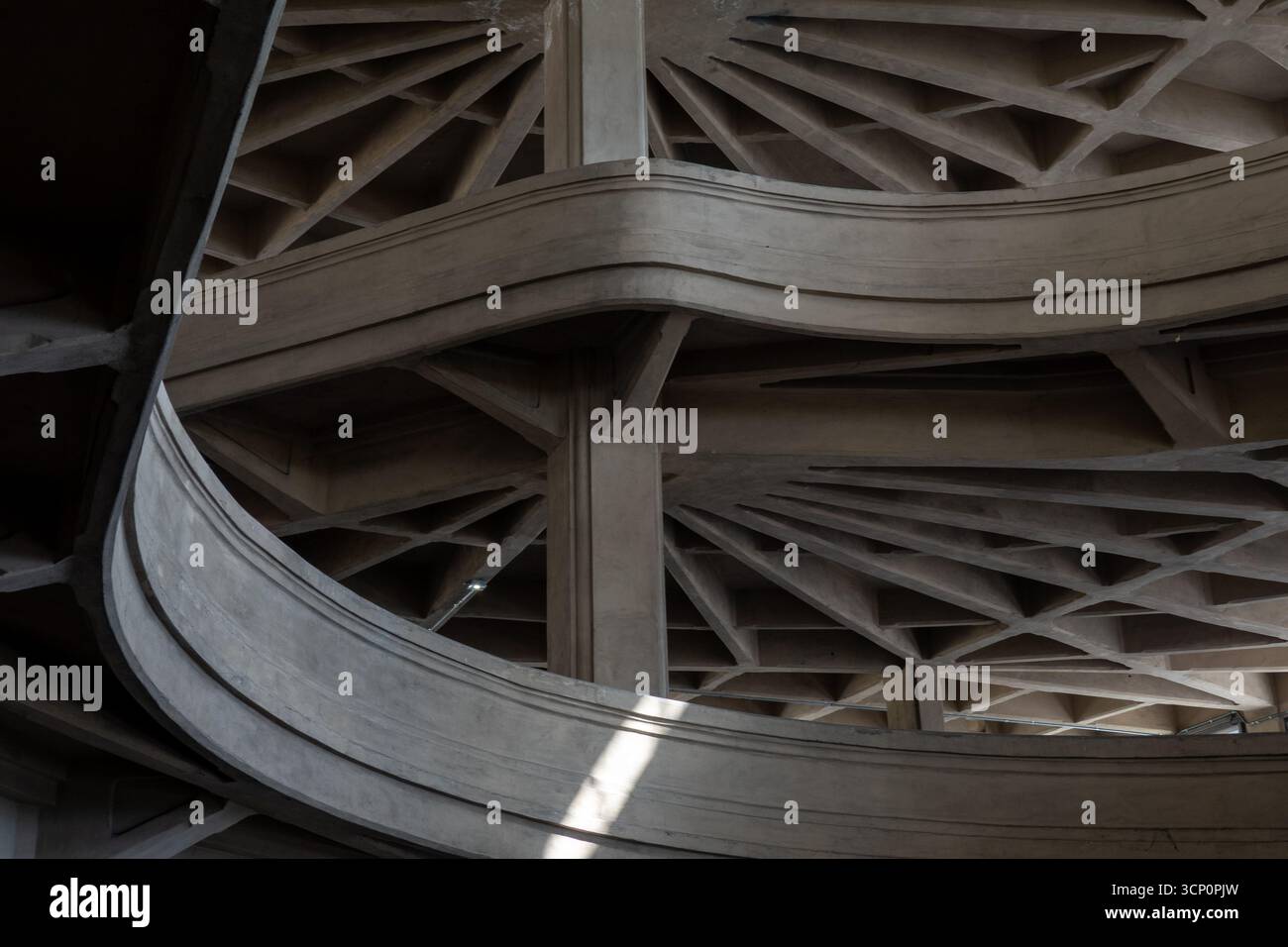 Interni circolari in cemento con ampie rampe curve, travi incrociate, ombre spettacolari. La simmetria architettonica mette in risalto l'arte ingegneristica e l'atmosfera industriale. Foto Stock