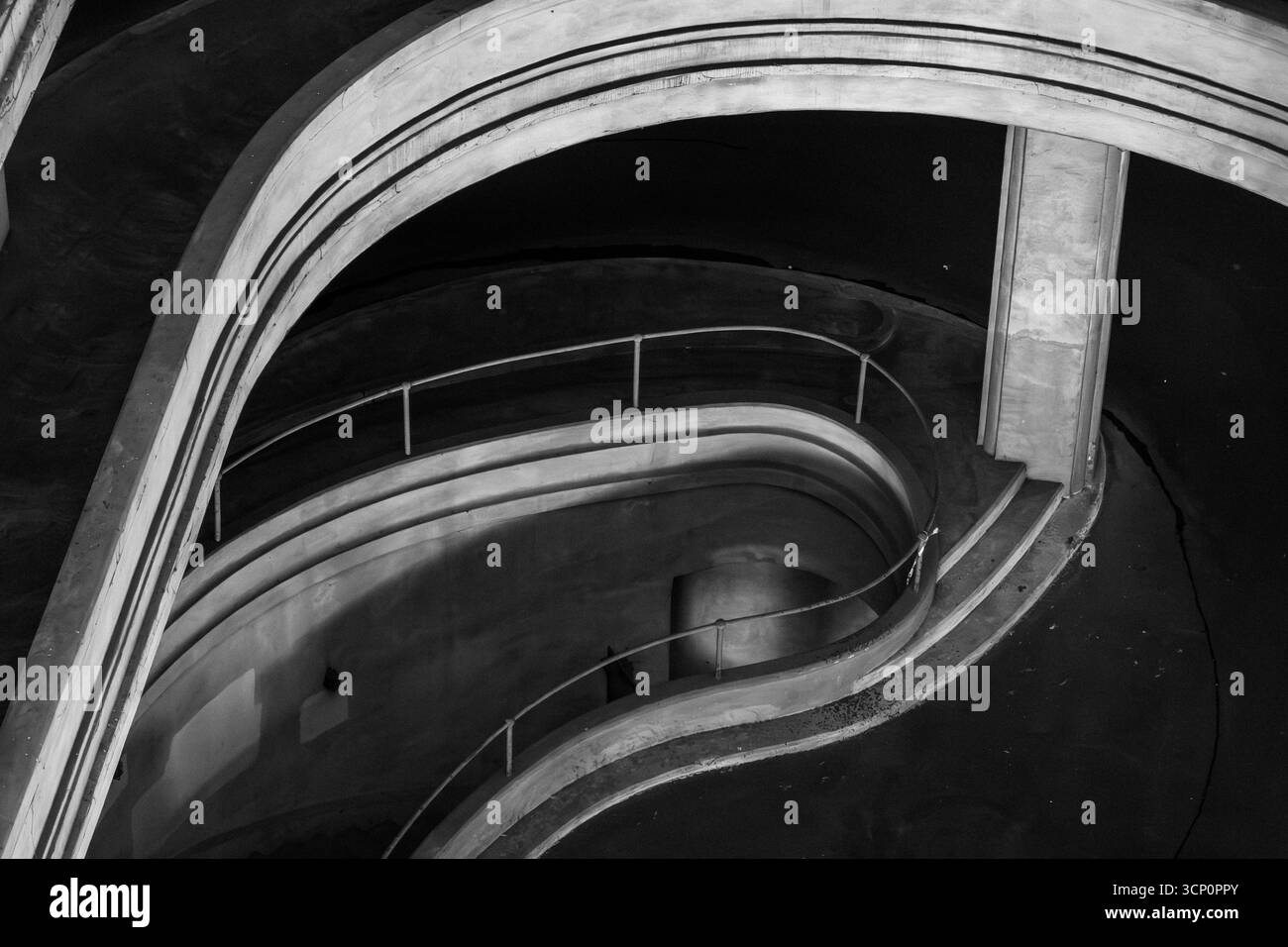 Scala a chiocciola monocromatica con pareti curve e guide a strati che mostrano eleganza architettonica profondità e flusso astratto in un suggestivo ambiente urbano Foto Stock