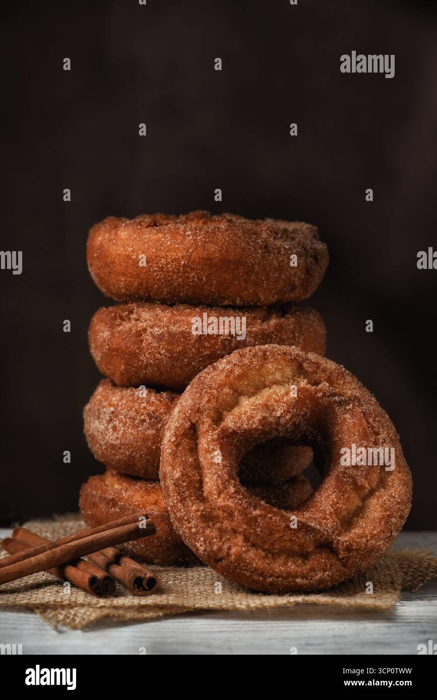 Una pila di ciambelle al sidro di mele appena preparate, una appoggiata sulla pila su uno sfondo marrone scuro macchiato con spazio per copiare. Foto Stock