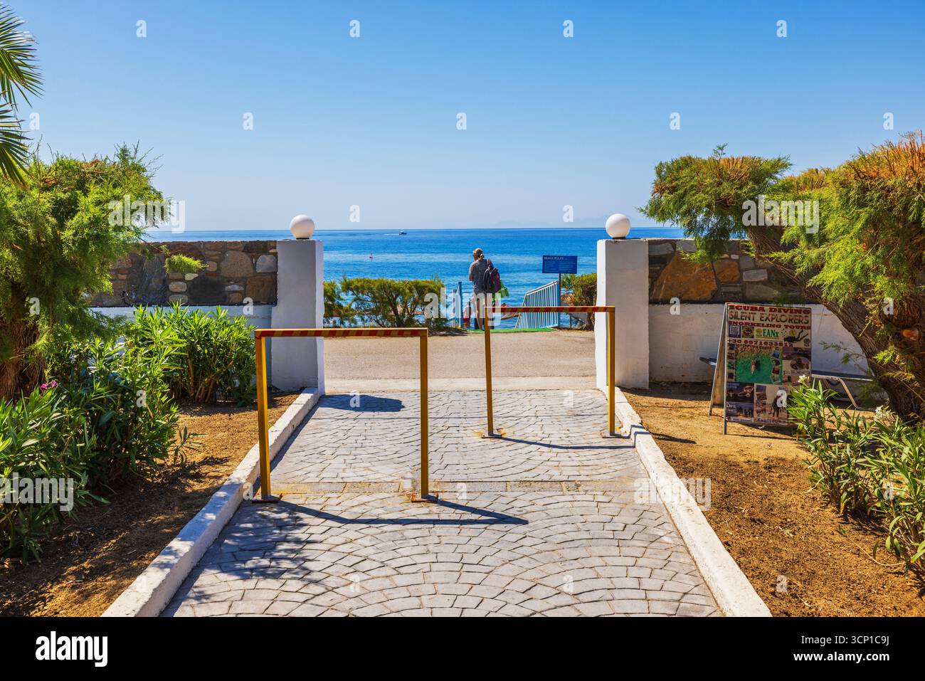 Uscita dell'hotel per la spiaggia sull'isola di Kos con una persona che cammina verso il Mar Egeo sullo sfondo. Grecia. Kos. Foto Stock