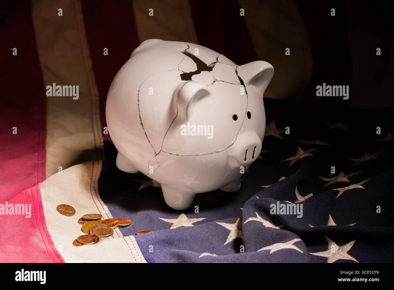 Un salvadanaio bianco fratturato e mal riparato posto sulla bandiera americana circondato da monete sparse. Foto Stock