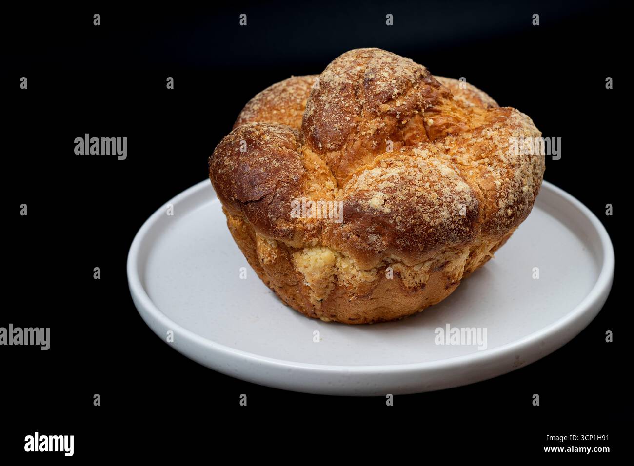 Primo piano di pane dolce fatto in casa con una copertura di briciole di zucchero e una crosta dorata su un piatto bianco. Perfetto per il design di panifici, pasticceria e dessert tradizionali Foto Stock