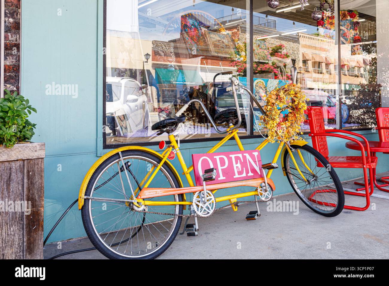 Lincolnton, Carolina del Nord, Stati Uniti - 14 luglio 2025: Bicicletta gialla costruita per due persone si appoggia contro il punto vendita, con un cartello "aperto". Foto Stock