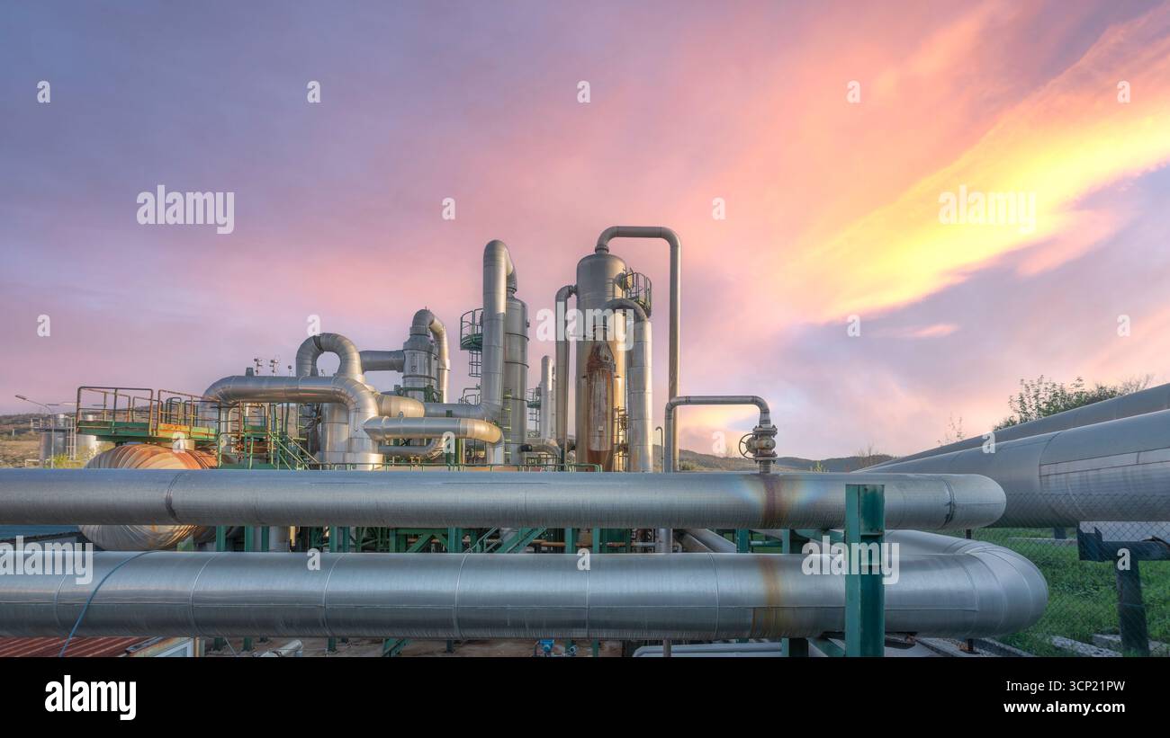 Gasdotti industriali geotermici al tramonto a Larderello, Toscana. Tubi a vapore e apparecchiature per la produzione di energia rinnovabile Foto Stock