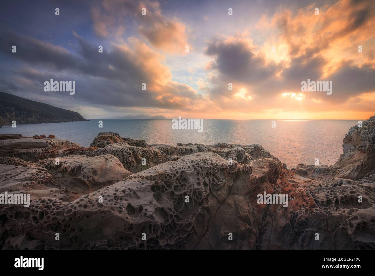 Spettacolare tramonto sulle rocce erose dal vento alle scogliere della Buca delle fate a Populonia, in Maremma. Nuvole dorate che si riflettono sul Mar Mediterraneo, Piombino, Italia Foto Stock