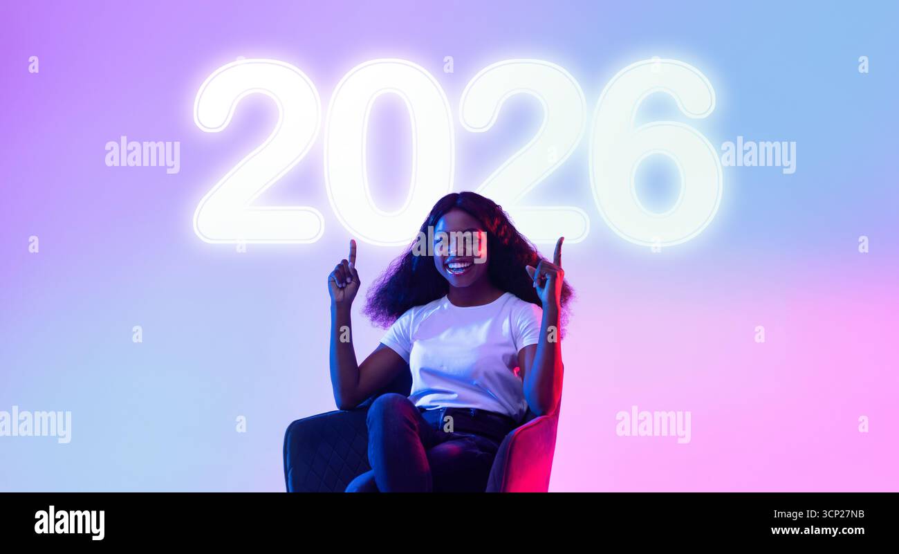 Giovane donna nera sorridente seduta in poltrona che offre spazio per il tuo annuncio in luce al neon Foto Stock