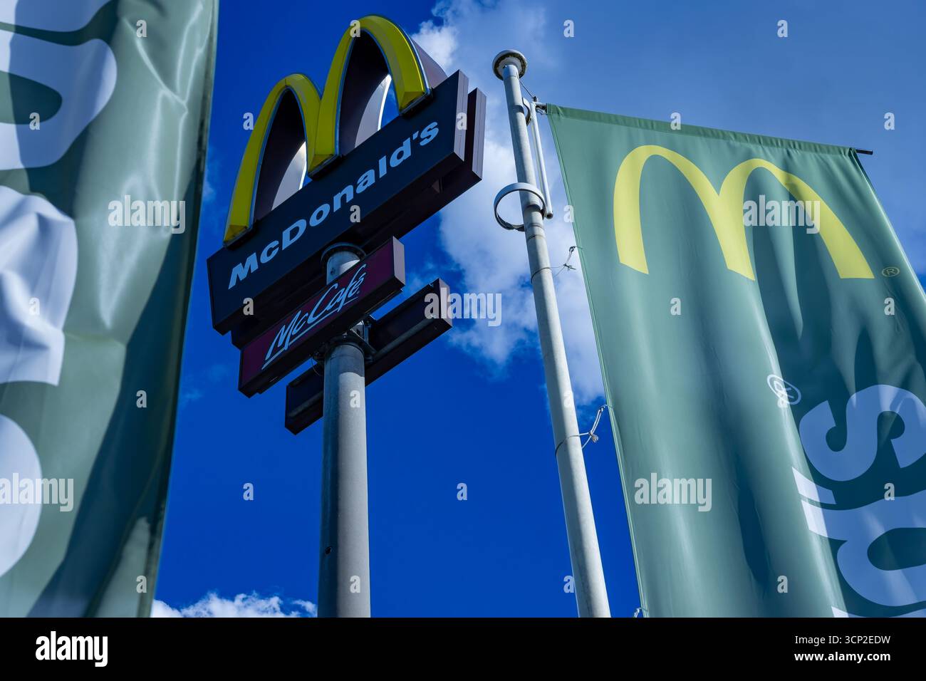 McDonald's e McCafé cartellone pubblicitario con bandiere sventolanti catturate contro un cielo estivo limpido in Germania, prospettiva verso l'alto. Foto Stock