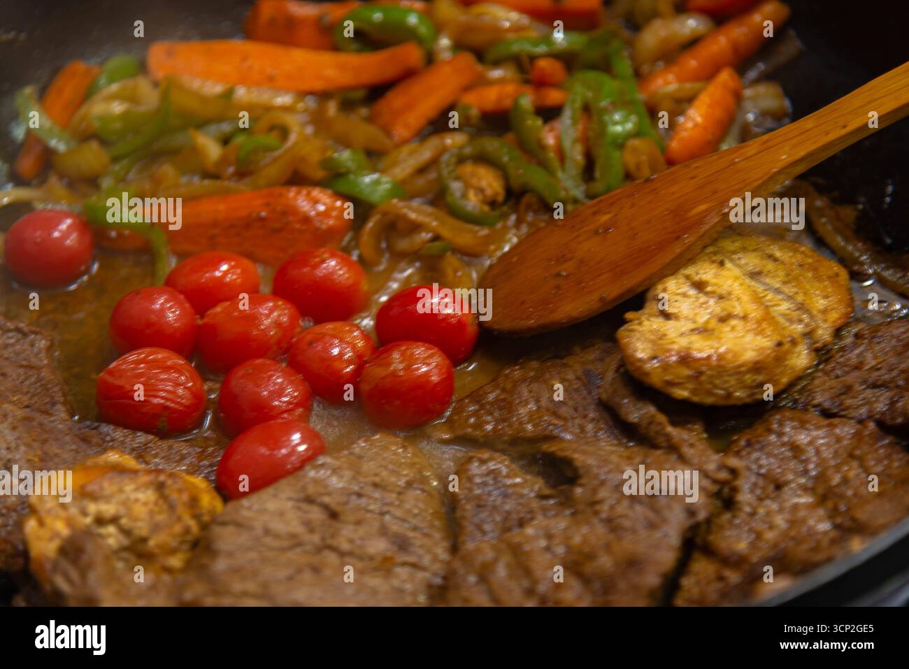 Bistecca con cipolle e pomodori rossi preparati in una cucina residenziale. Foto Stock