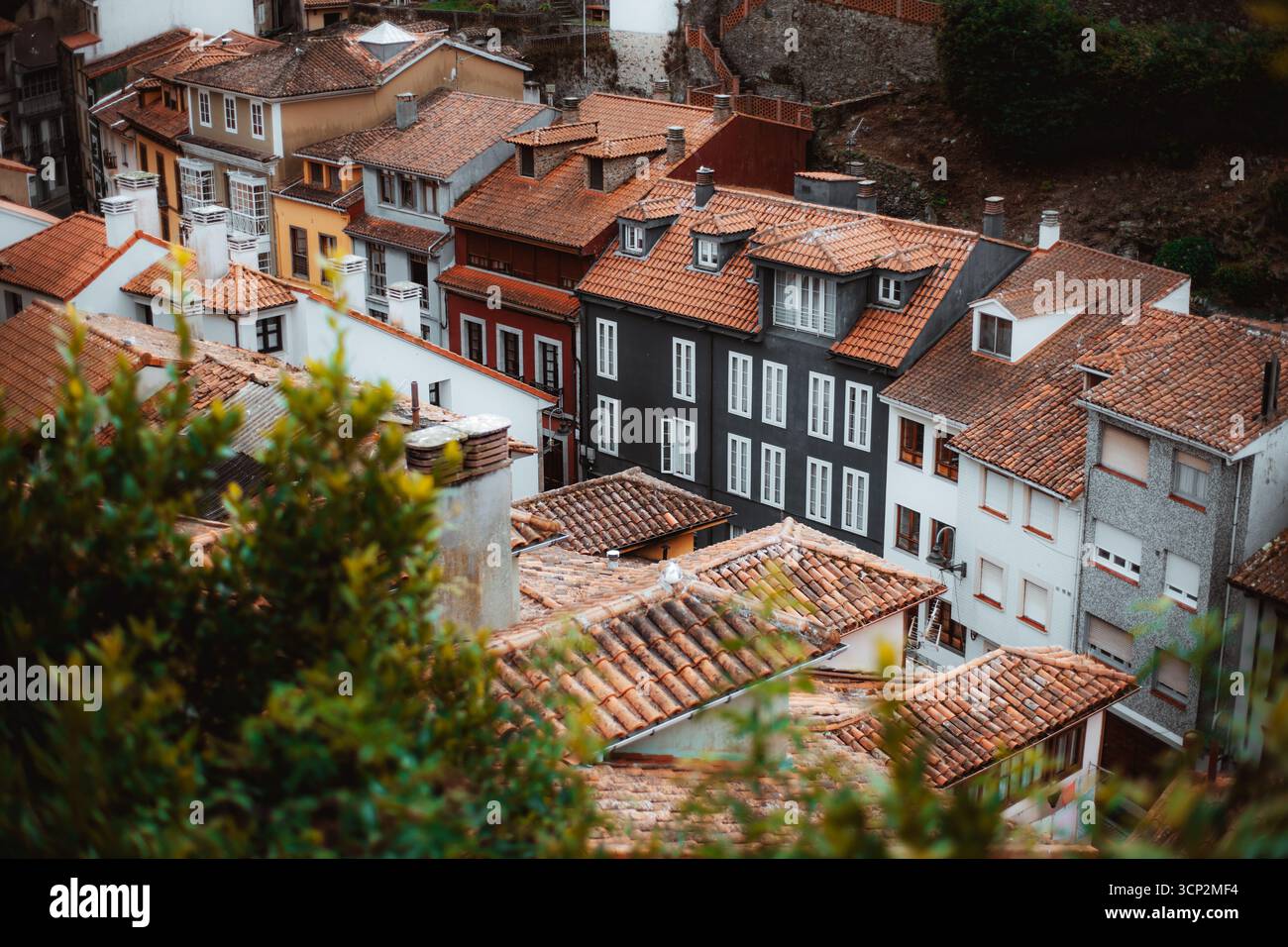 Vista pittoresca delle tradizionali case spagnole con tetti di tegole rosse e facciate colorate in una storica cittadina collinare, incorniciata dal verde e dall'architettura rustica Foto Stock