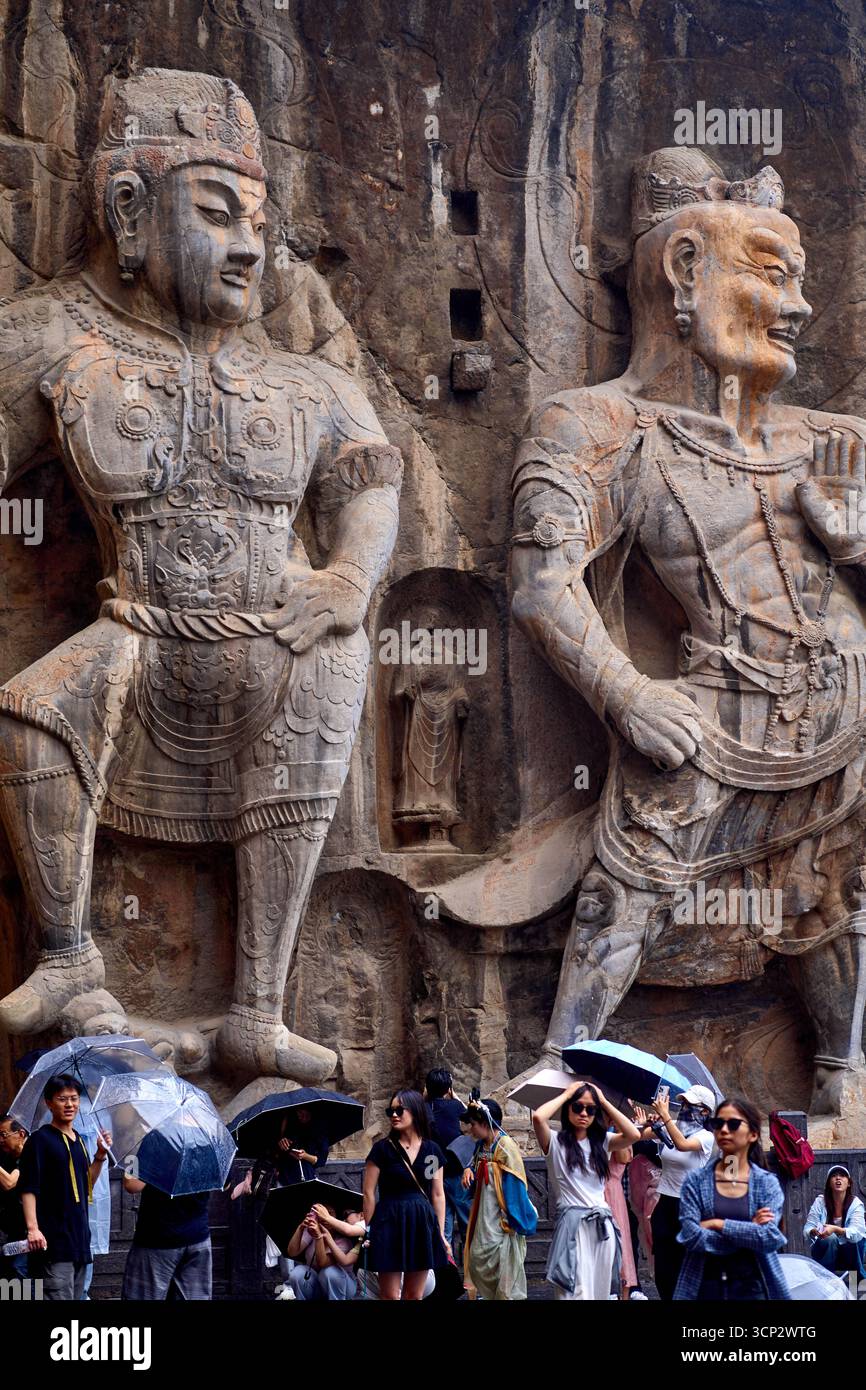 I giganteschi guardiani delle Grotte di Longmen/Grotte di Longmen a Luoyang con persone sotto la pioggia Foto Stock