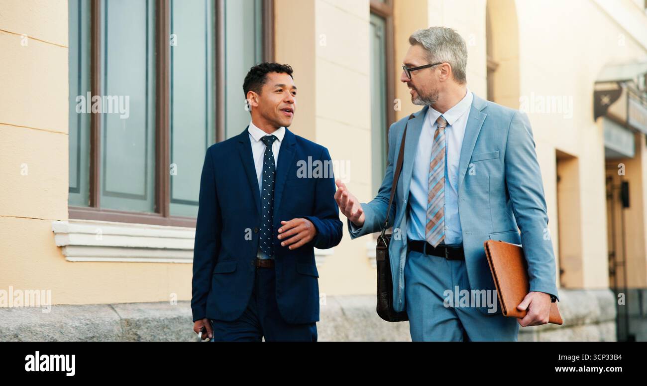 Affari, avvocati e uomini in città, conversazione e feedback per cause legali, mentore e conversazione. All'aperto, persone e avvocati in strada, discussione Foto Stock