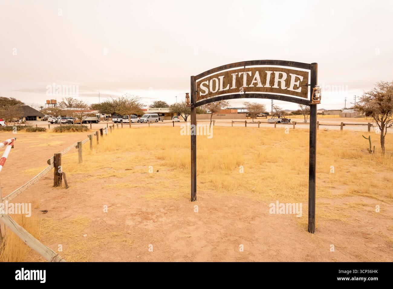 Il remoto insediamento desertico di Solitaire in Namibia - 27 agosto 2025: Presenta un cartello con il nome della città, adagiato su dune di sabbia dorata e. Foto Stock