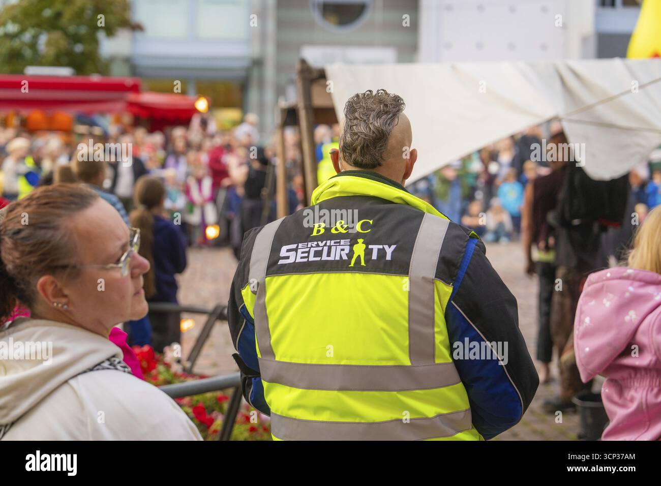 Una guardia di sicurezza monitora l'evento tra una folla di visitatori al festival cittadino, Feuernacht, Sindelfingen, Germania Foto Stock
