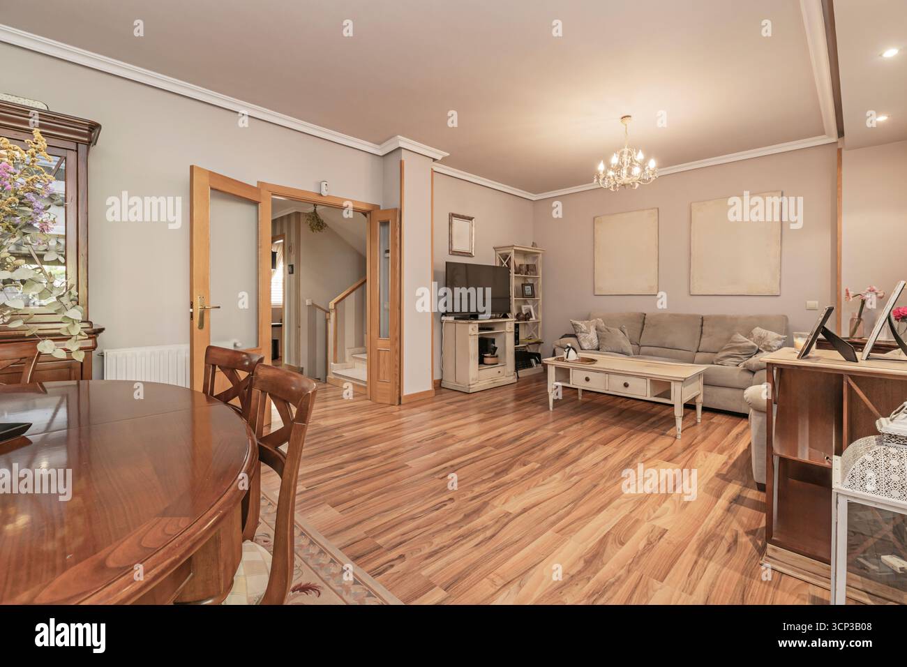 un divano in biancheria grigia, un tavolino da caffè in legno restaurato e una zona pranzo con sedie in metallo. Foto Stock