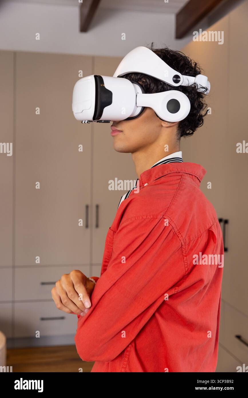 Uomo che incrocia le braccia indossando un visore vr bianco e una giacca rossa in piedi accanto agli armadi, spazio copia Foto Stock