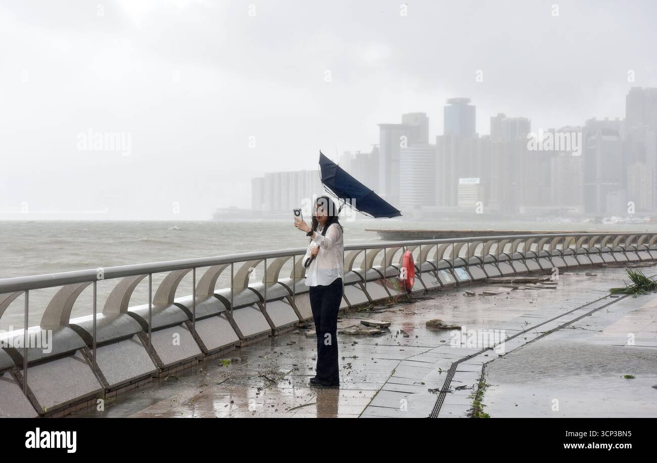 Hong Kong, Cina. 24 settembre 2025. Una donna scatta foto in mezzo al forte vento e alle precipitazioni al Victoria Harbour di Hong Kong, nel sud della Cina, 24 settembre 2025. L'Osservatorio di Hong Kong ha emesso il segnale uragano n. 10, l'avvertimento di livello superiore, alle 2:40 ora locale di mercoledì mentre il super tifone Ragasa gira. Questa è stata la seconda volta che l'allarme più alto è stato attivato quest'anno dopo che il tifone Wipha è passato il 10 luglio. Hong Kong non ha ripetuto il segnale n. 10 in un anno dal 1964. Crediti: Chen Duo/Xinhua/Alamy Live News Foto Stock