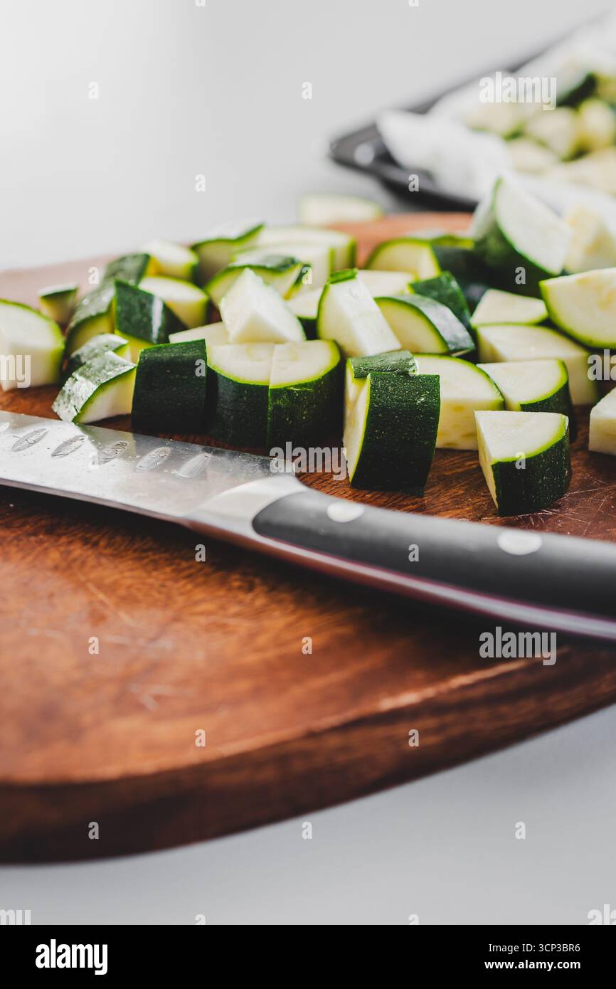 zucchine tritate su tavola di legno con coltello accanto, preparazione di verdure fresche per ricette salutari Foto Stock zucchine tritate su tavola di legno con coltello accanto, preparazione di verdure fresche per ricette salutari Foto Stock