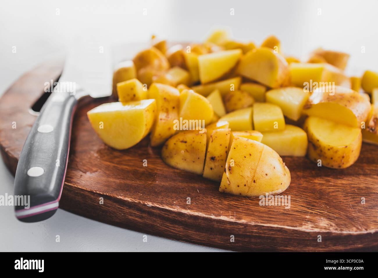 patate novelle tritate su un asse di legno con un coltello accanto, preparazione di verdure fresche per ricette salutari Foto Stock patate novelle tritate su un asse di legno con un coltello accanto, preparazione di verdure fresche per ricette salutari Foto Stock