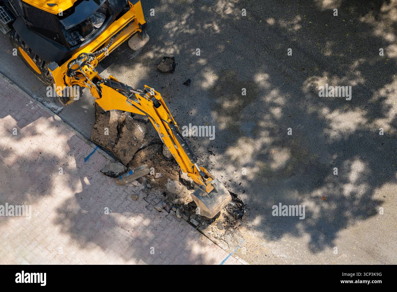 Vista dall'alto dell'escavatore giallo che scava asfalto per la manutenzione stradale Foto Stock