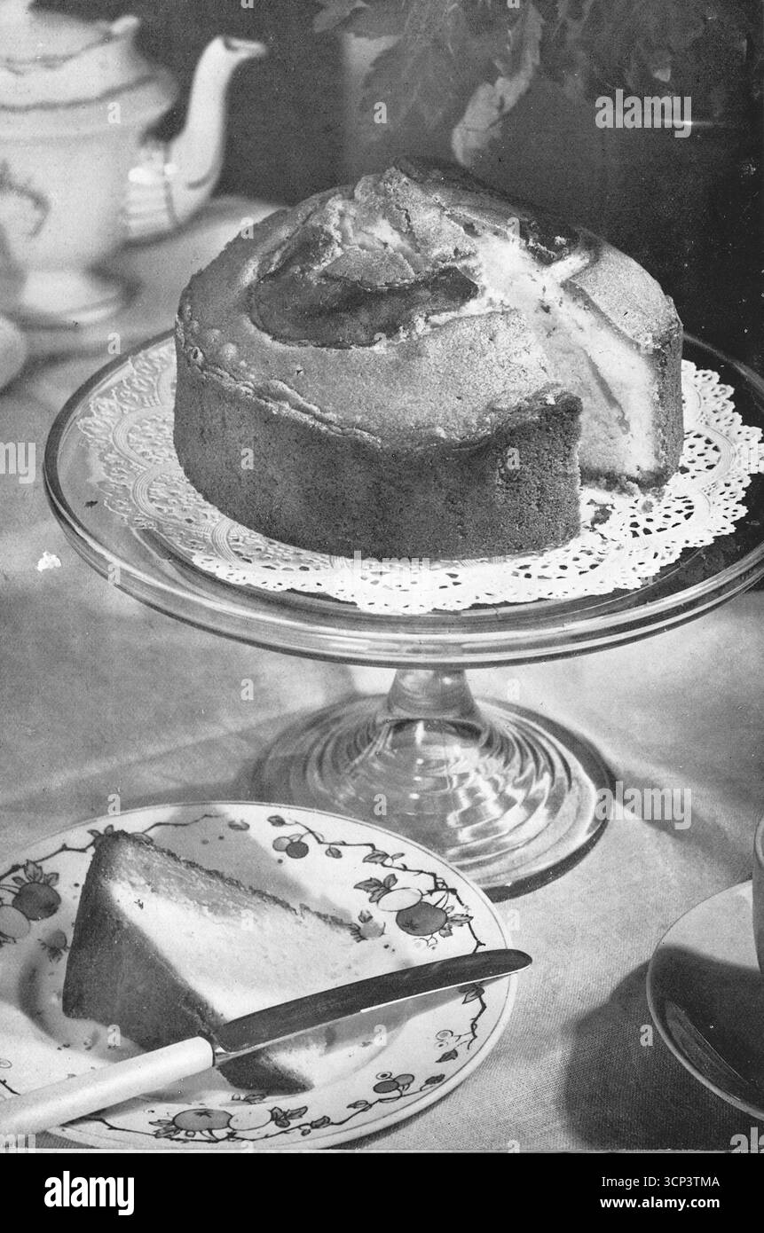 Da un forno Vulcan: Una grande torta in spugna su un supporto per torte di vetro e una fetta su un piatto laterale. Da una fotografia stampata che originariamente apparve nella pubblicazione, The Vulcan Cook Book, che fu pubblicato nel 1936 dalla Vulcan Stove Company di Exeter, Inghilterra. Foto Stock