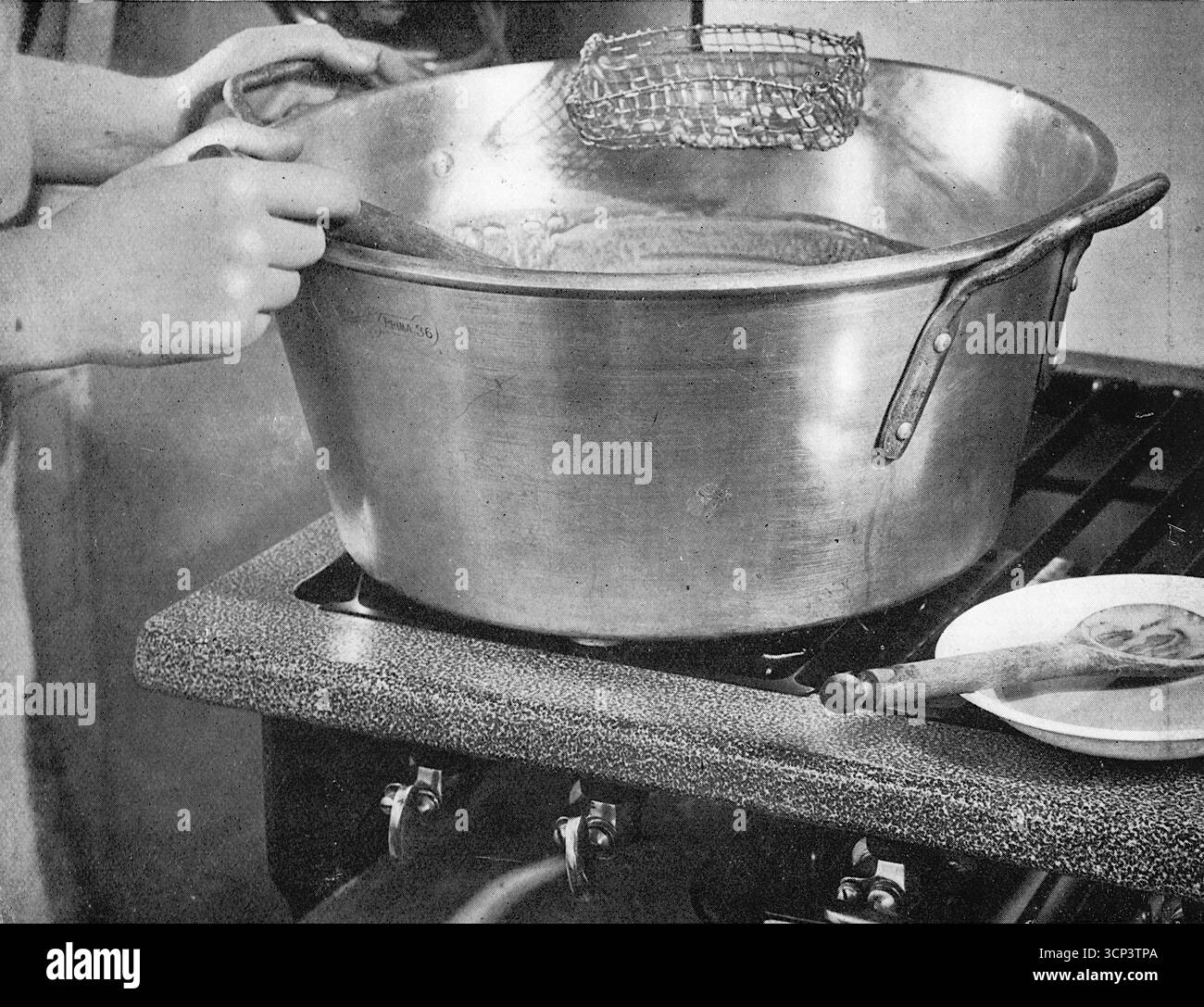 Una grande teglia aperta, tipica di quelle utilizzate per la preparazione delle marmellate negli anni '1930, su un fornello Vulcan. Da una fotografia stampata che originariamente apparve nella pubblicazione, The Vulcan Cook Book, che fu pubblicato nel 1936 dalla Vulcan Stove Company di Exeter, Inghilterra. Foto Stock