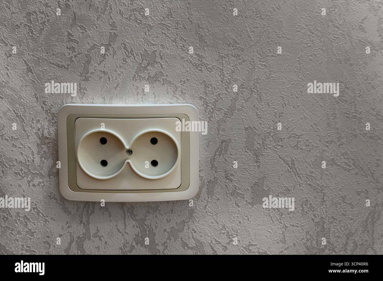 Primo piano di una doppia presa elettrica bianca montata su una parete in gesso testurizzato. La foto illustra le infrastrutture elettriche domestiche e la Foto Stock