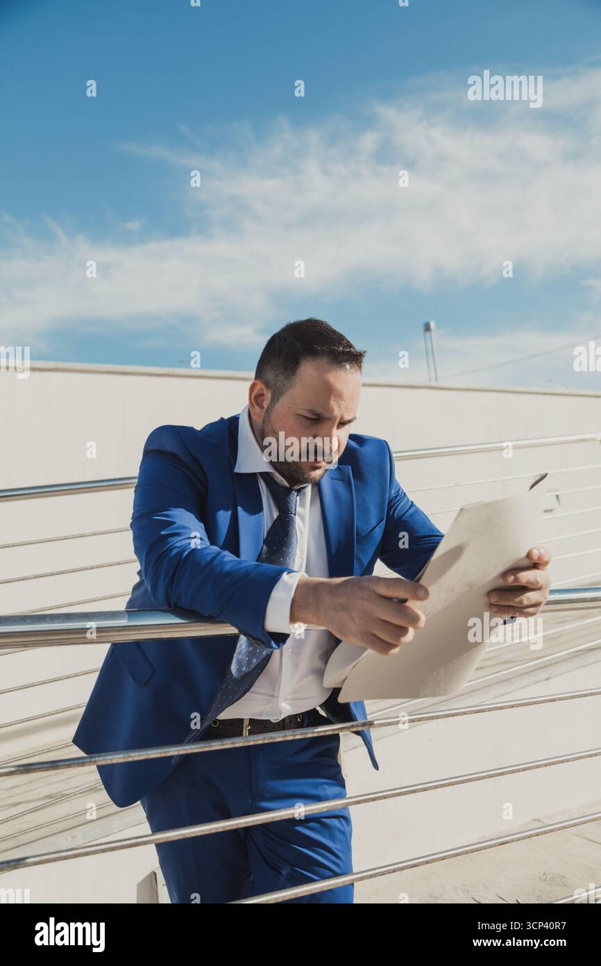 Uomo professionista che legge Un documento finanziario sotto il sole Foto Stock