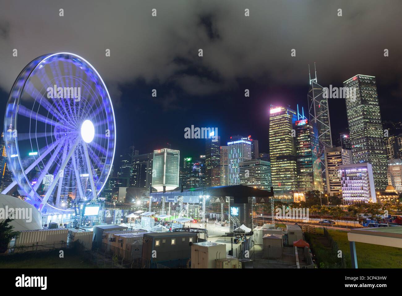 Hong Kong - 19 luglio 2017: Vivace paesaggio notturno caratterizzato da una ruota panoramica e grattacieli illuminati del quartiere centrale di Hong Kong Foto Stock Hong Kong - 19 luglio 2017: Vivace paesaggio notturno caratterizzato da una ruota panoramica e grattacieli illuminati del quartiere centrale di Hong Kong Foto Stock