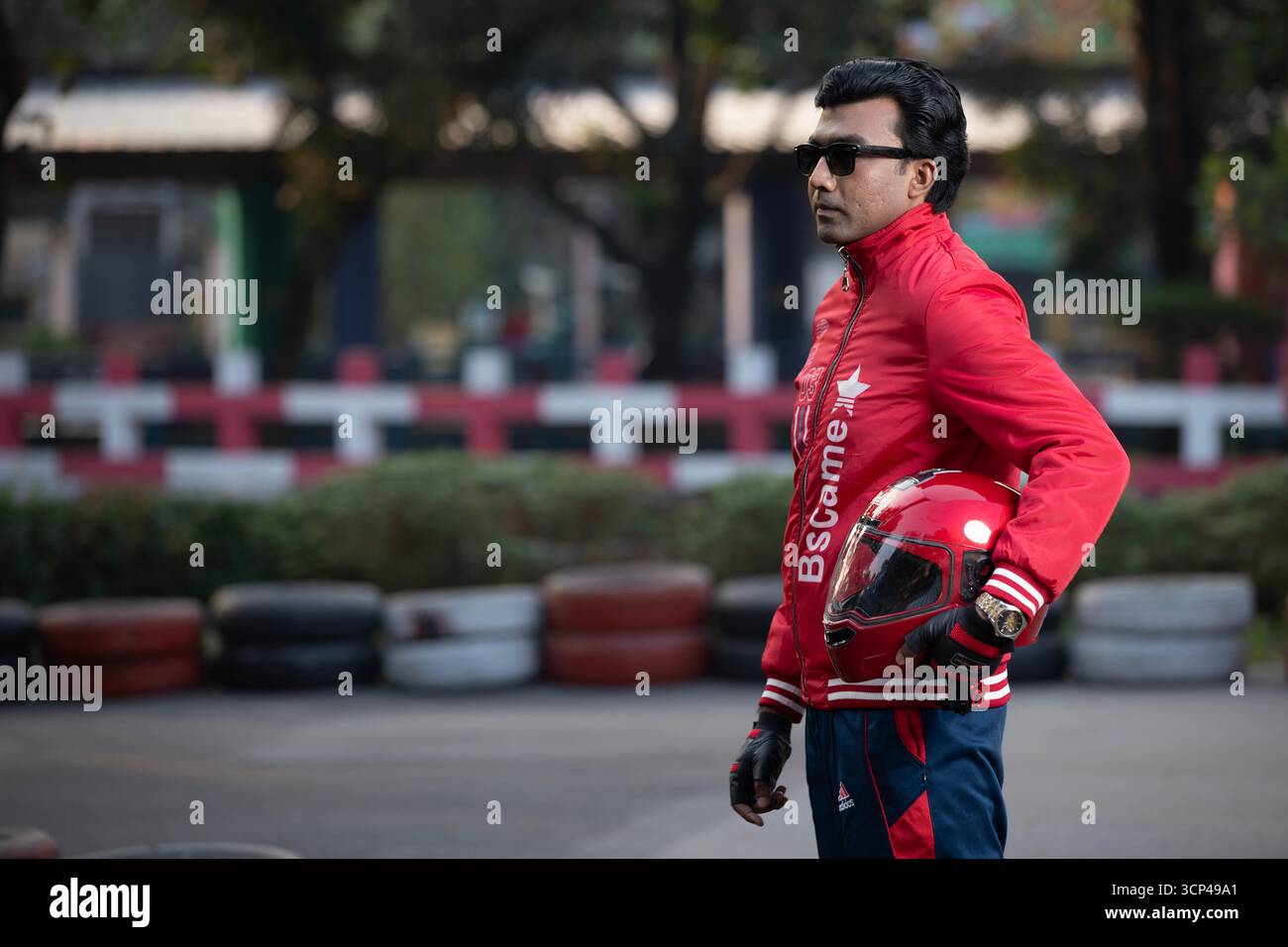 Un uomo con giacca rossa e occhiali da sole con casco da moto rosso Foto Stock