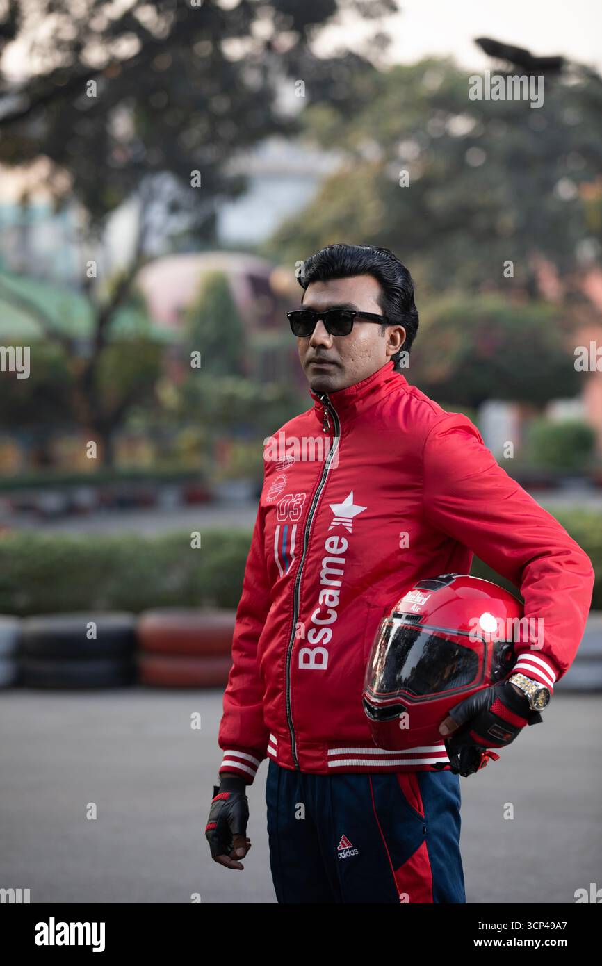 Un uomo con giacca rossa e occhiali da sole con casco da moto rosso Foto Stock