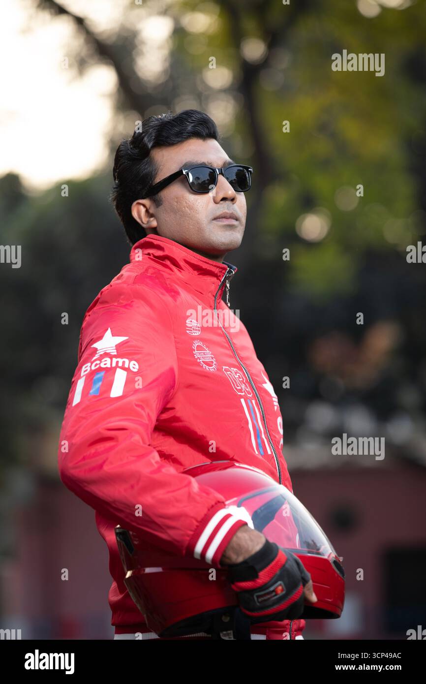 Un uomo con giacca rossa e occhiali da sole con casco da moto rosso Foto Stock