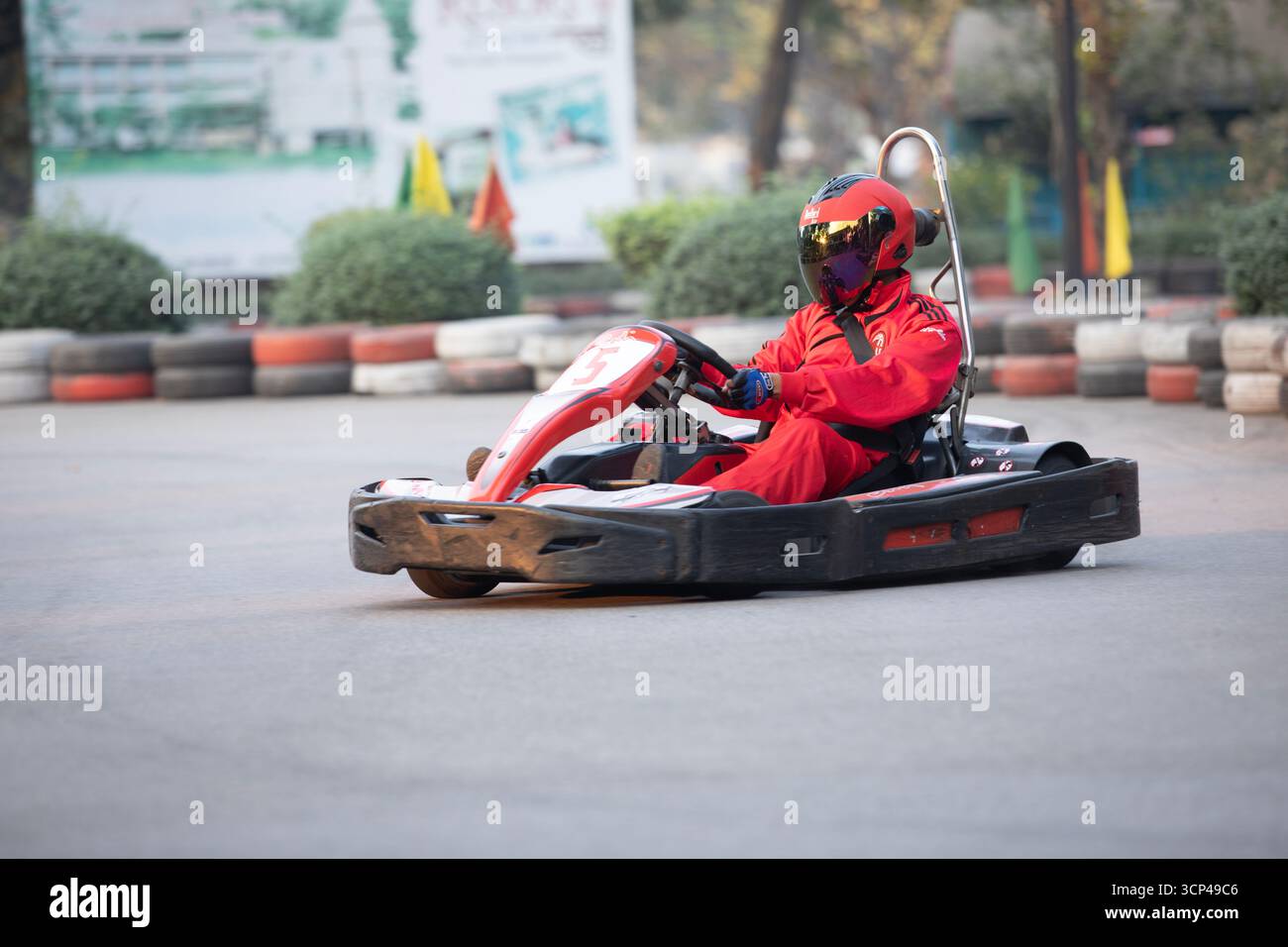 Una persona in una tuta da corsa rossa che guida un go-kart su un autodromo Foto Stock
