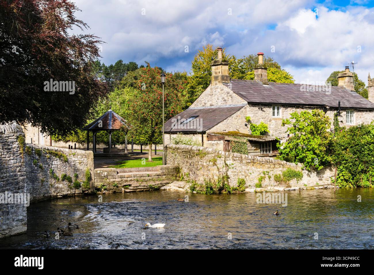 Ammira il ponte Sheepwash sul fiume Wye fino al cottage e al Market Stand nel villaggio del Peak District. Ashford in the Water, Bakewell, Derbyshire, Inghilterra Foto Stock