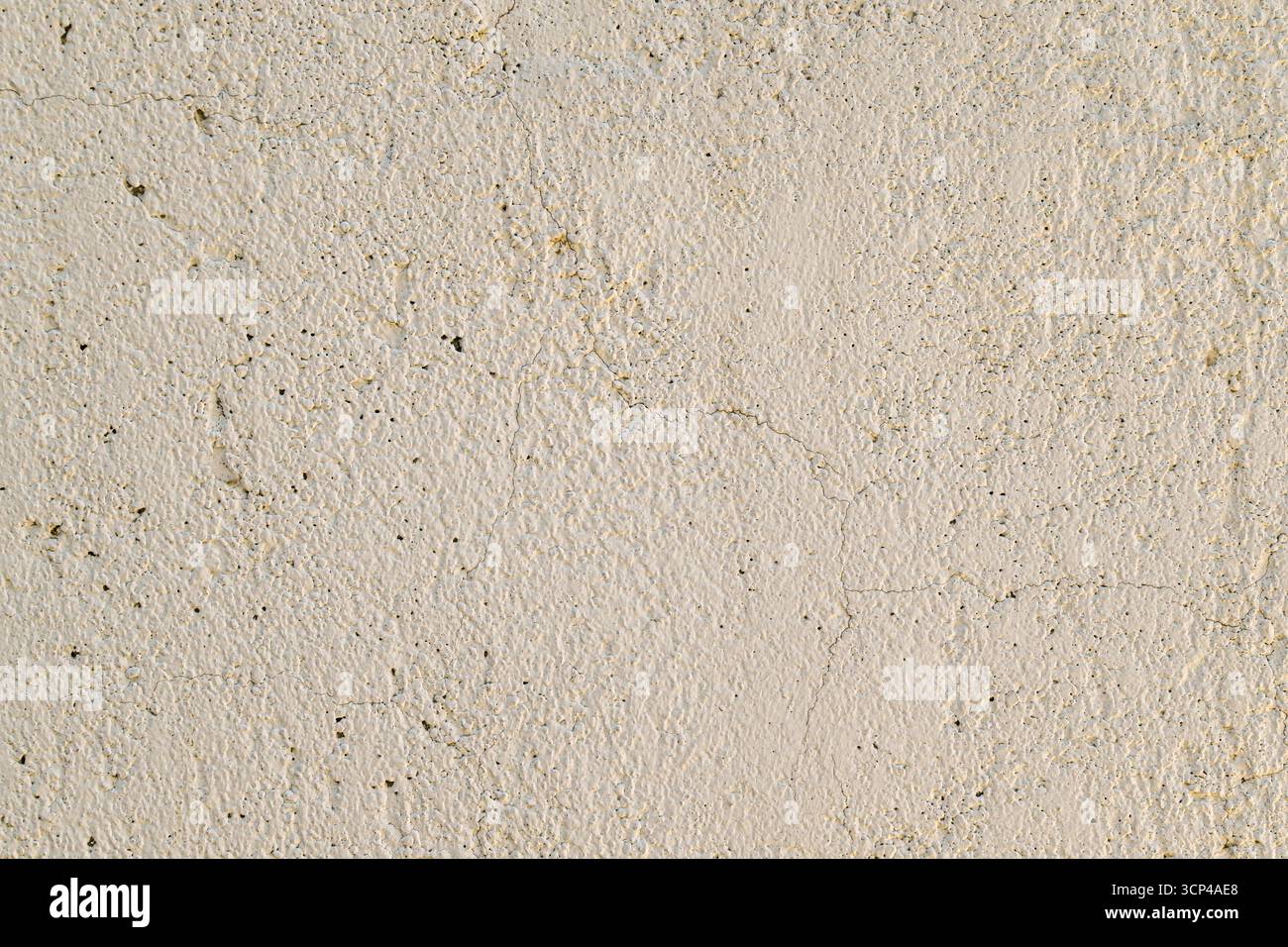 Un muro con uno sfondo bianco e qualche piccolo foro. La parete è realizzata in cemento e ha una consistenza ruvida Foto Stock