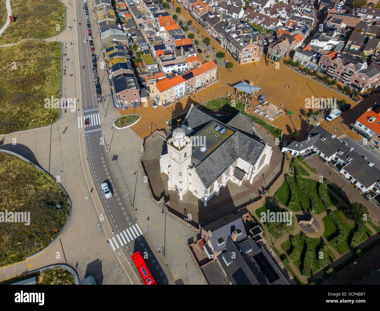 Veduta aerea di una cittadina compatta centrata su una chiesa con facciata bianca con cupola e torre dell'orologio, circondata da strade acciottolate, bolla rossa e grigia con tetto Foto Stock
