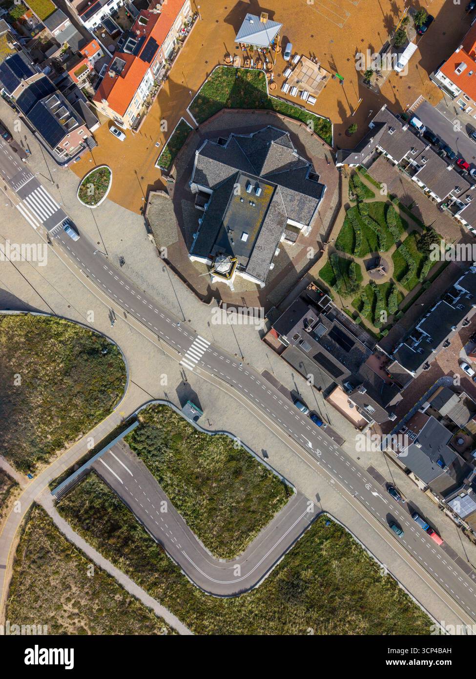 Veduta aerea di una cittadina compatta centrata su una chiesa con facciata bianca con cupola e torre dell'orologio, circondata da strade acciottolate, bolla rossa e grigia con tetto Foto Stock