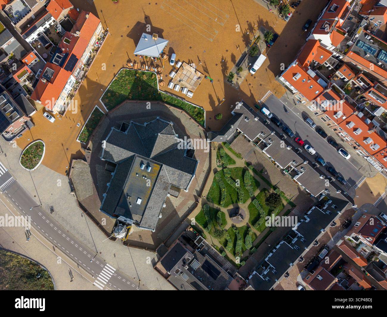 Veduta aerea di una cittadina compatta centrata su una chiesa con facciata bianca con cupola e torre dell'orologio, circondata da strade acciottolate, bolla rossa e grigia con tetto Foto Stock