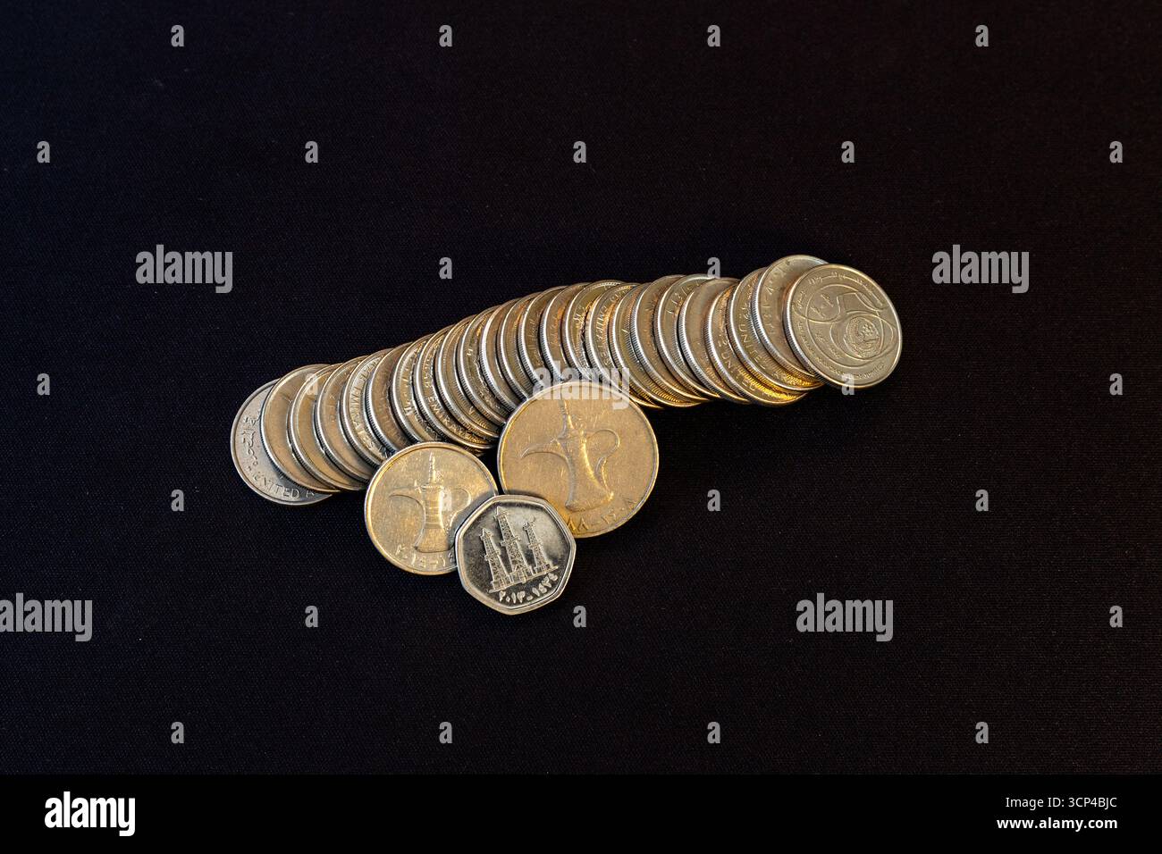 Monete di Dirham degli Emirati Arabi Uniti impilate con tradizionale caffettiera Dallah araba Foto Stock