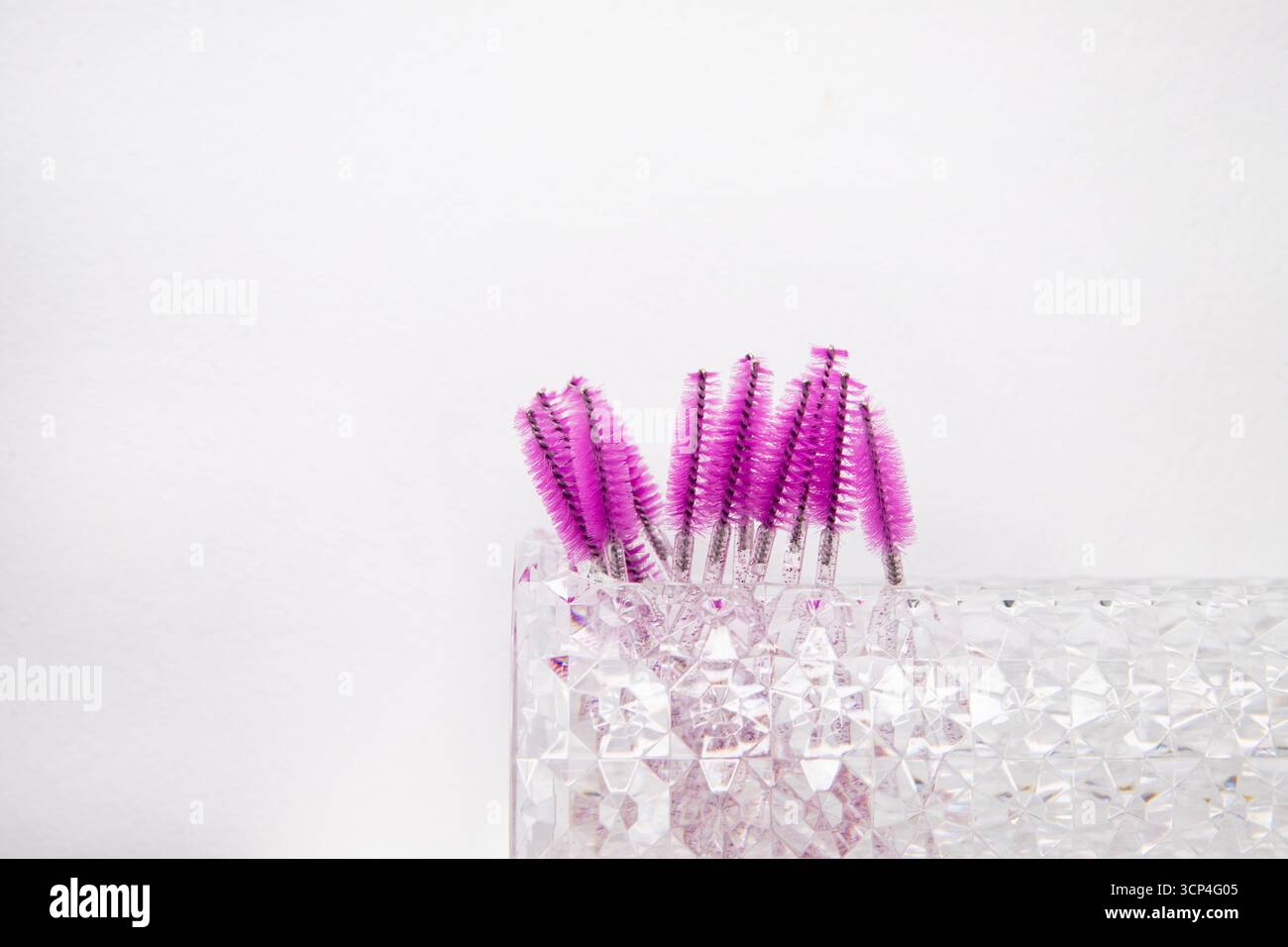 Truccatrice per la cura delle ciglia e delle sopracciglia. Su sfondo bianco pennelli per prolunghe ciglia e colorazione sopracciglia e accanto alla posizione per una A. Foto Stock