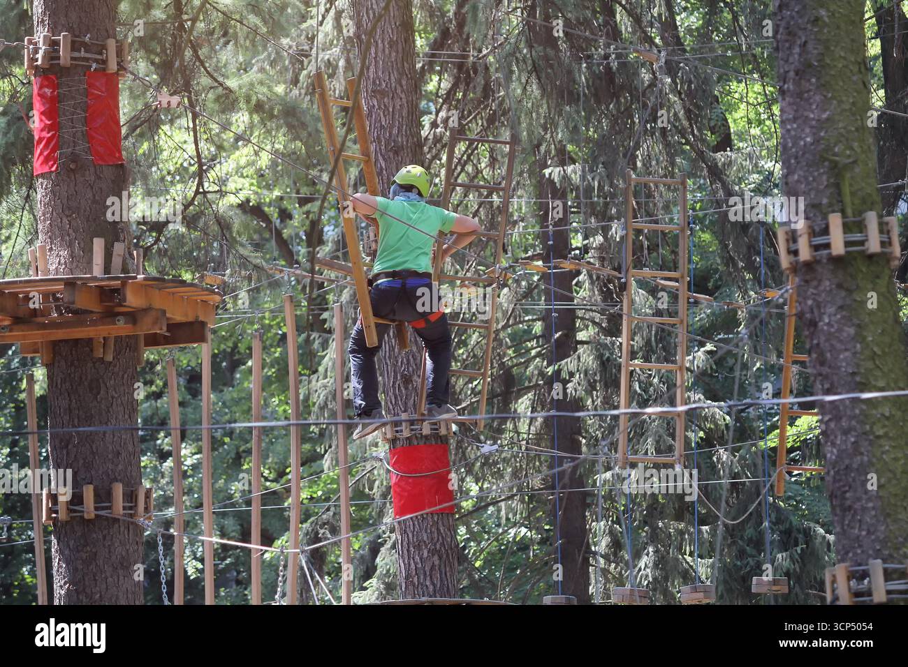 Persone in un parco di corda per casco in vacanza attiva nella foresta. Vacanza estrema Foto Stock