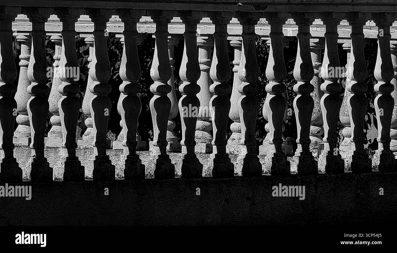Pilastri e recinzione in calcestruzzo – equilibrio tra luce e ombra. Tonalità monocromatiche. Foto Stock