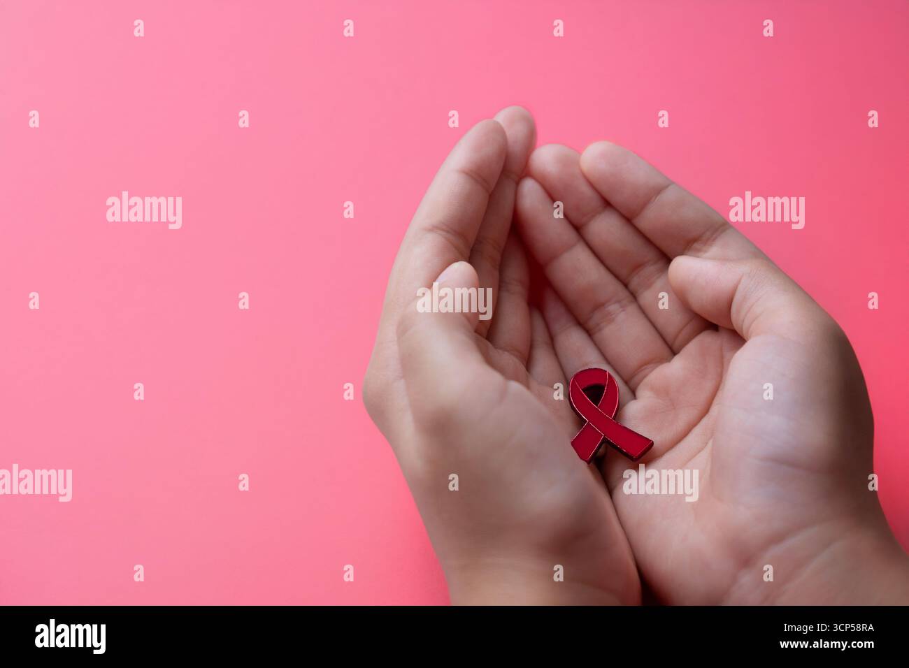 Mani con un nastro rosso di consapevolezza su sfondo rosso. HIV, concetto di sensibilizzazione all'AIDS. Copia spazio per il testo. Foto Stock