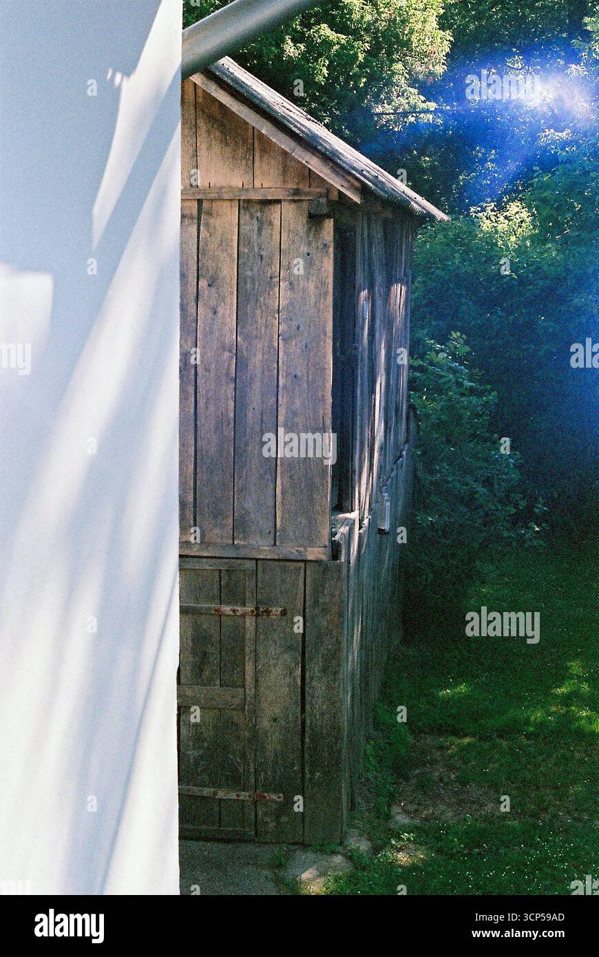 Capannone di legno dietro una casa per il fine settimana circondata da alberi. Foto analogica con riflessi, creando un'atmosfera calda e nostalgica. Foto Stock