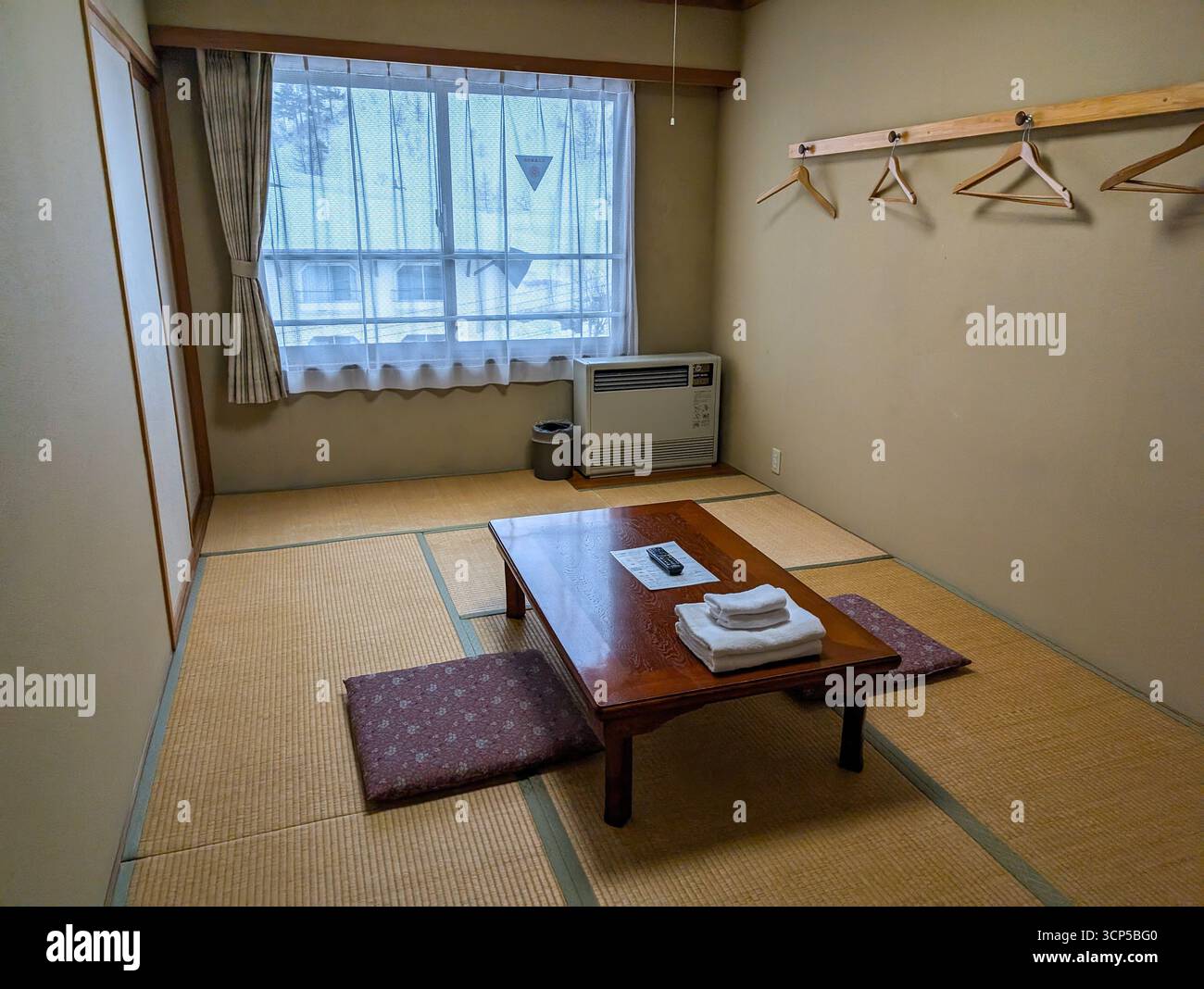 Interno di una tradizionale camera d'hotel giapponese con materassino tatami, basso tavolo e zabuton. Foto Stock