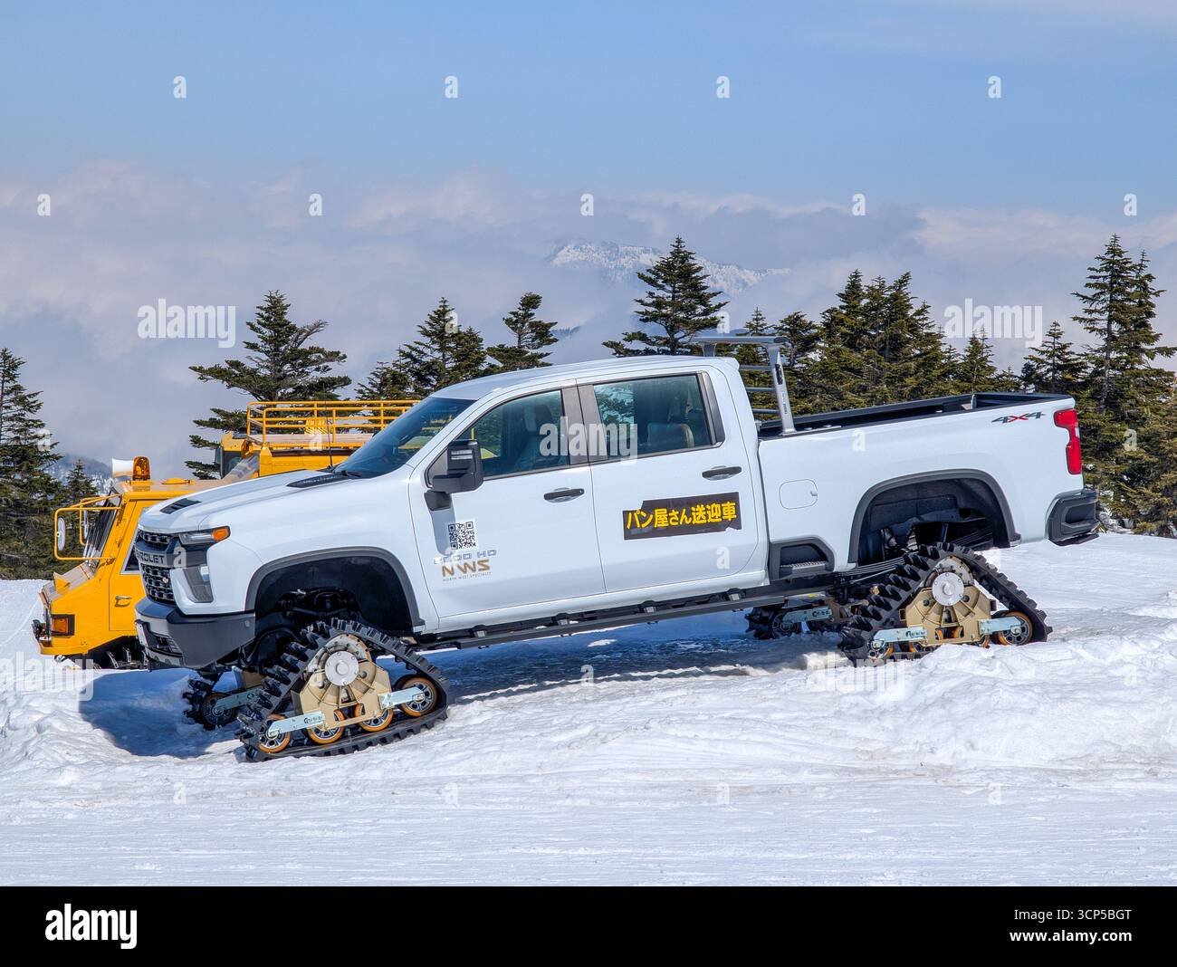 Pick-up 4x4 modificato con cingoli continui parcheggiati su una cima innevata. Foto Stock