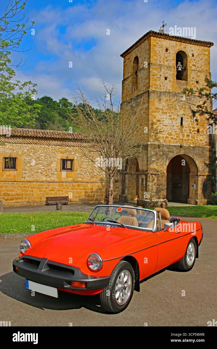 Un'auto sportiva britannica a due posti rossa lucida degli anni '1980 parcheggiata di fronte a uno storico edificio spagnolo in pietra. Foto Stock